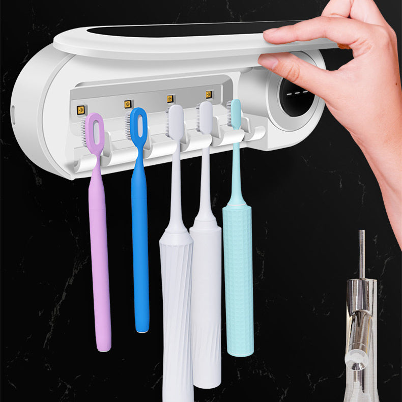 The holder on a dark wall with five toothbrushes hanging under it